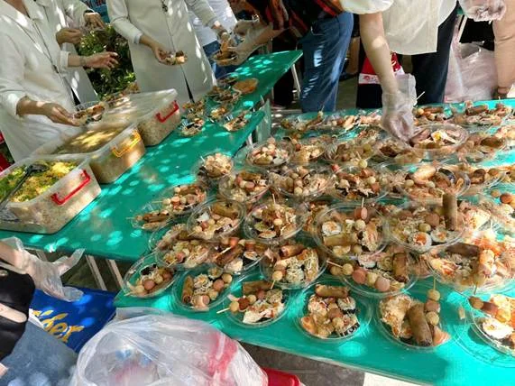 A group of people standing at a table with food

AI-generated content may be incorrect.